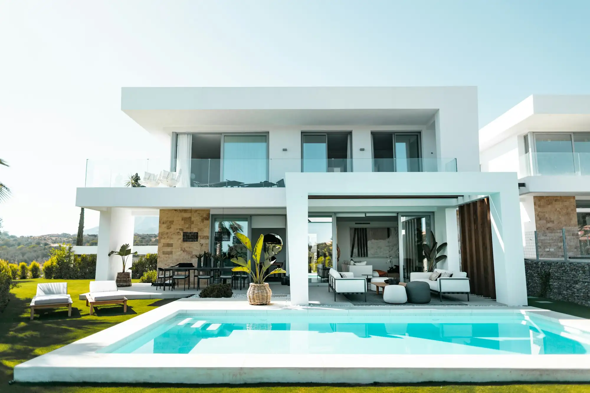 Casa moderna de vidro e concreto com piscina ao entardecer